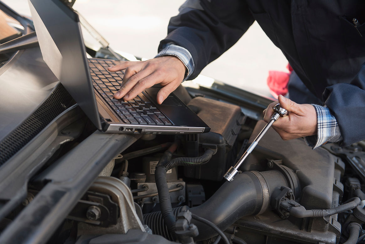 Mechanic using laptop while repairing car