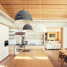 Modern pendant lights over long wood kitchen island
