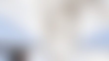 Delicate white lace curtain billows against a clear blue sky, with sunlight streaming through, creating an airy and serene mood.