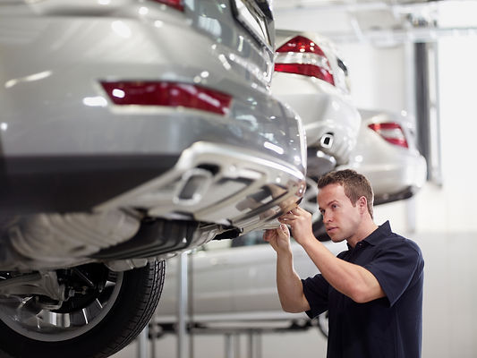 Auto technician examining the undercarriage of a car to check for hidden accident damage