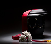 Black urn with red tape and flower arrangement