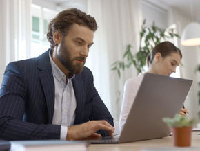 Man in a suit looking at laptop screen.