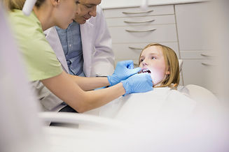Dental assistant flossing girls teeth