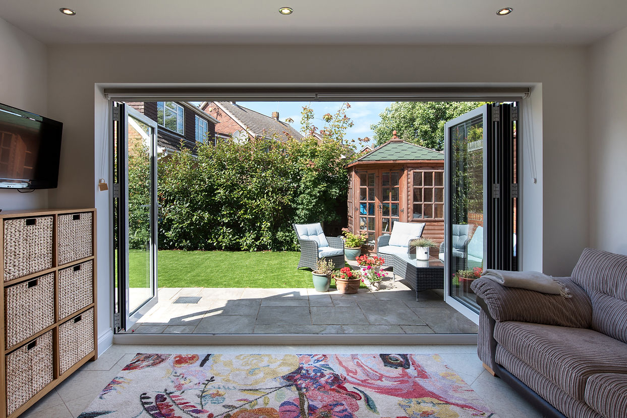 Spacious living area with open glass doors leading to a garden