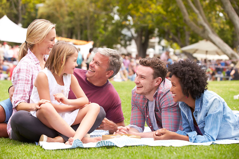 Family gathering on a sunny day with green grass and visible text.