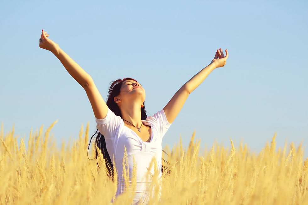 Joyful woman standing in a golden wheat field with open arms celebrating personal freedom