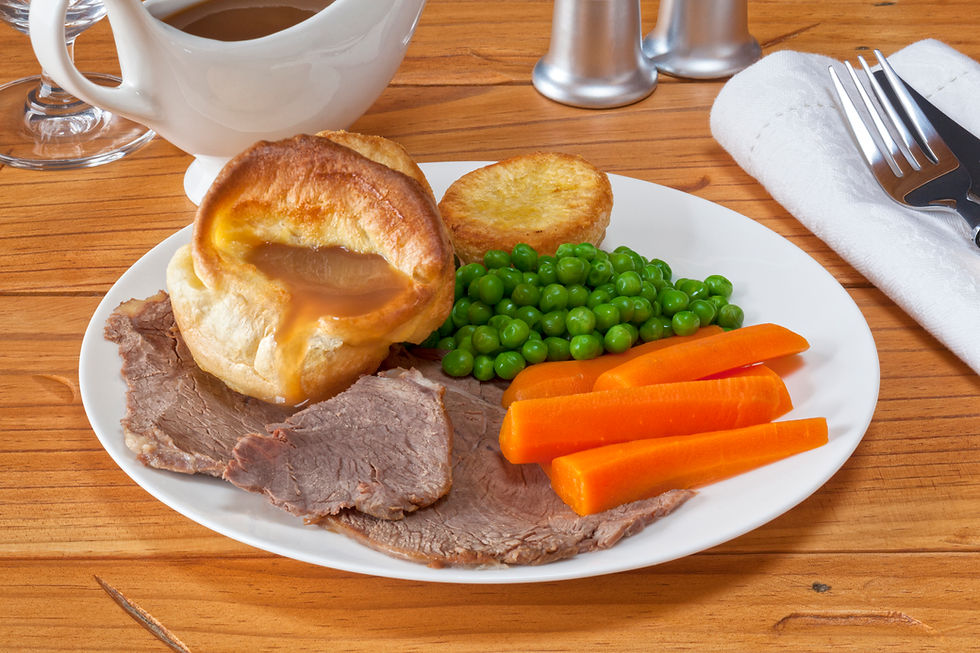 Traditional British roast dinner with beef, Yorkshire pudding, carrots, and peas