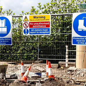 A variety of signs on a construction site fence