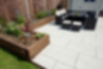 A general view of a back garden patio with white porcelain slabs, tiles, paving and wooden