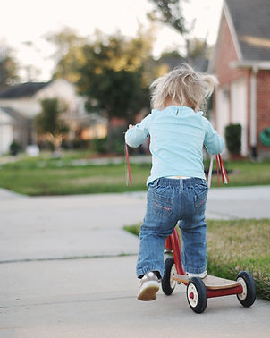Young child riding scooter in a safe residential neighborhood in Guyana