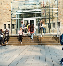 High school students walking up and down stairs that goes in and out of a school building