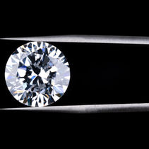 Diamante rotondo luminoso tenuto con pinzette su sfondo nero; Eva gioielli.