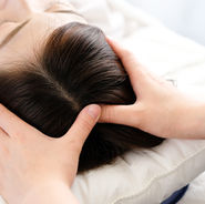 A therapist performing an aromatherapy head and scalp massage, using essential oils to relieve stress, improve circulation, and promote relaxation.