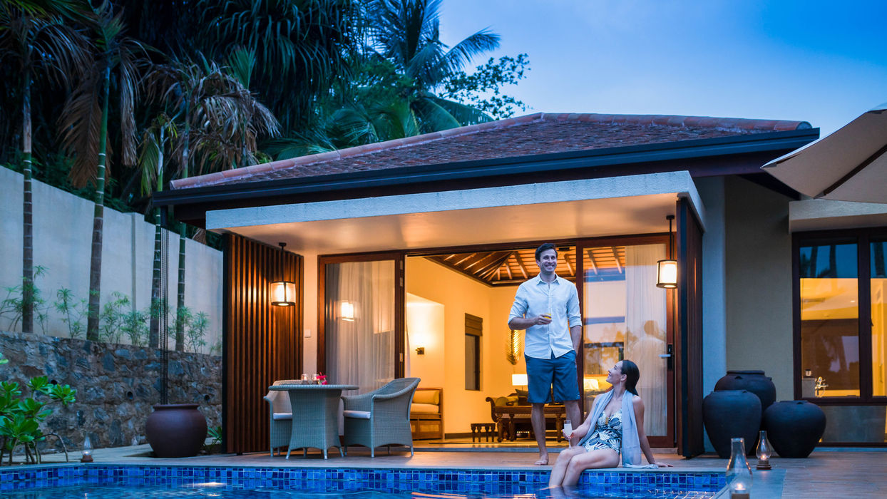 Couple relaxing by the  pool in their one bedroom villa 