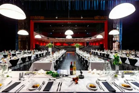 Elegant banquet hall with decorated tables and stage setup.