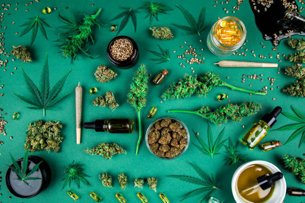 Assorted cannabis products including buds, leaves, oils, and capsules on a green background.