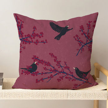 Cushion mockup with black birds on berry branches against a mauve
background.