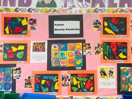 Colorful classroom bulletin board displaying children’s abstract art projects inspired by Wassily Kandinsky, with each piece labeled by student name and accompanied by small photos of the children creating their work.