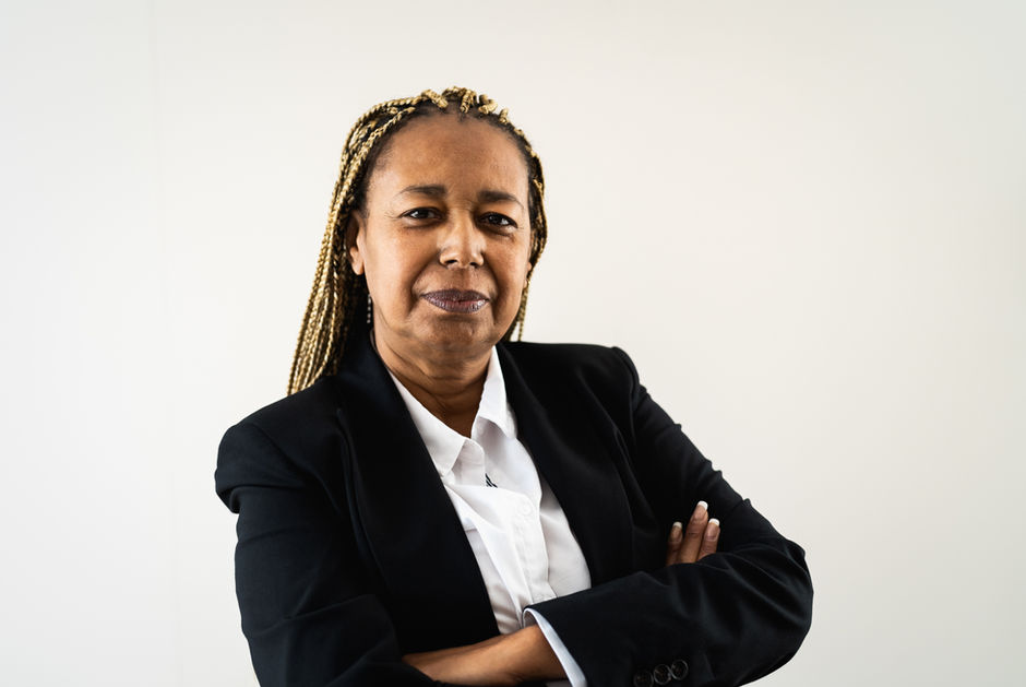 A grinning older Black woman with her arms crossed, looking powerful