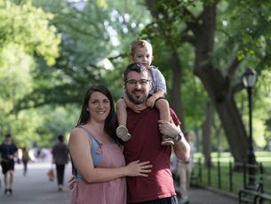 Anica, a client of the perinatal intensive outpatient program and Early Head Start, and her husband are standing with Luka on her husband's shoulders. They are in a park.
