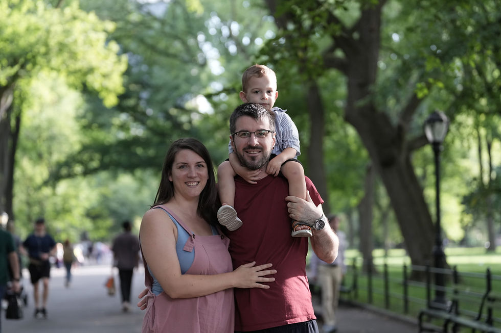 Anica, a client of the perinatal intensive outpatient program and Early Head Start, and her husband are standing with Luka on her husband's shoulders. They are in a park.
