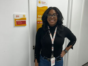 Therese Despeine standing smiling outside her office door.