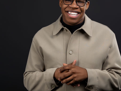 Jayln, a WIOA student turned staffer stands smiling against a black background.