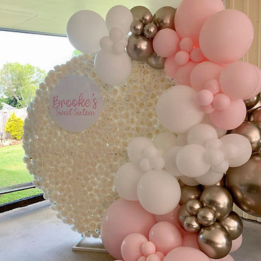 Balloon garland installation in blush pink and white at a baby shower in Cairns