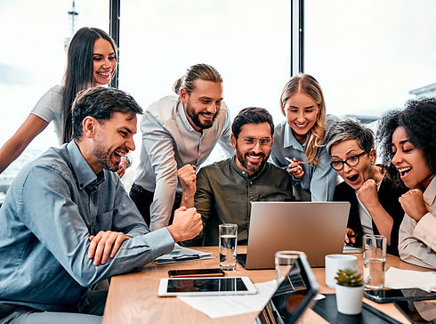 Team aus Männern und Frauen sitzt vor einem Laptop und ist freudig aufgeregt