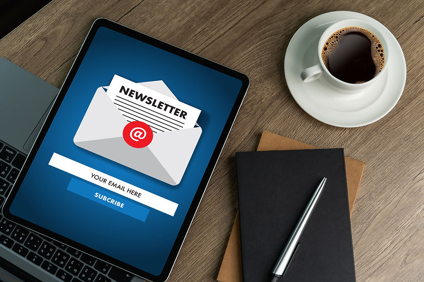 Tablet mit Newsletteranmeldung neben Kaffeetasse und Notizbuch