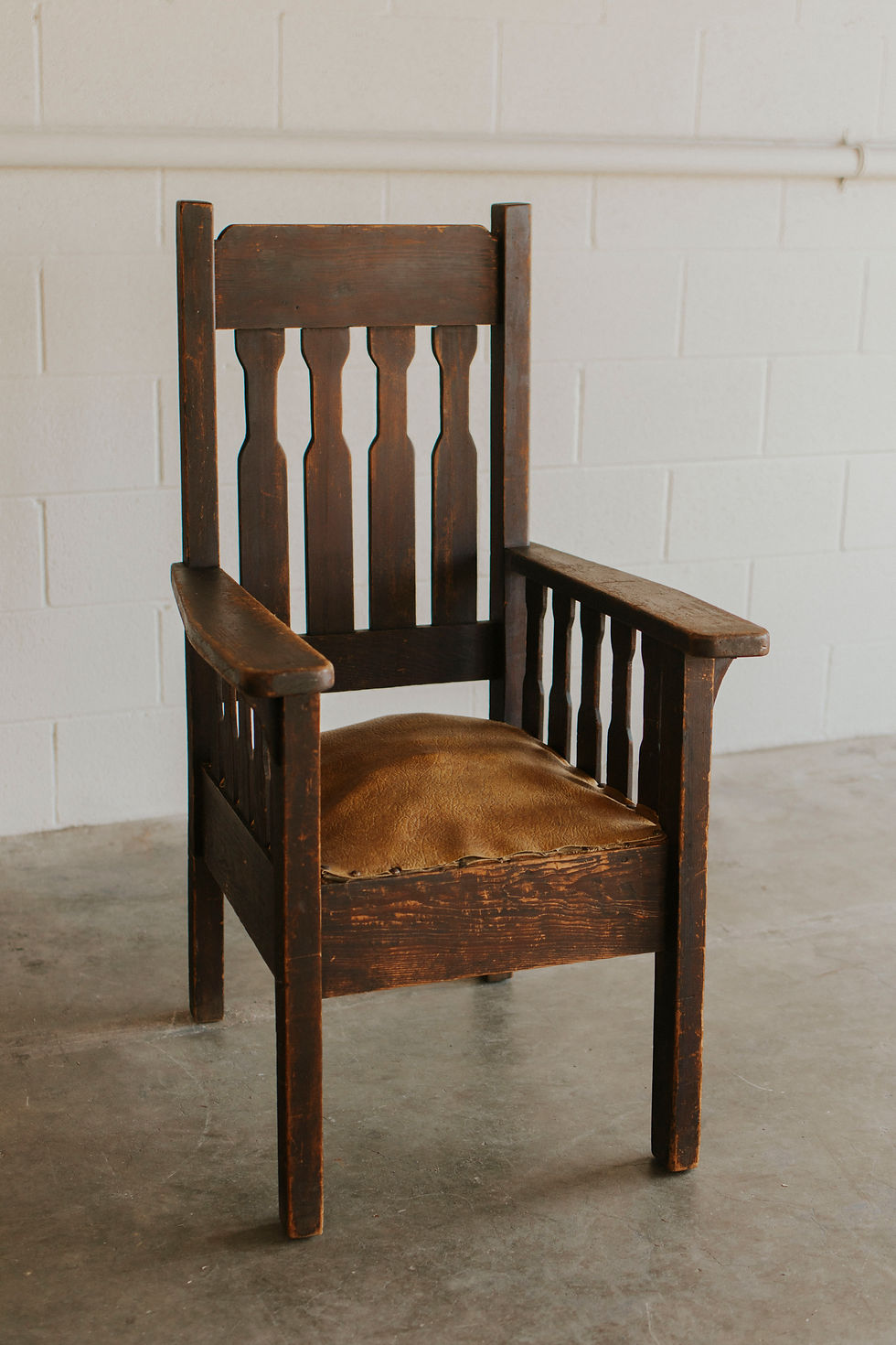 Dark wood armchair with slatted back and brown leather seat