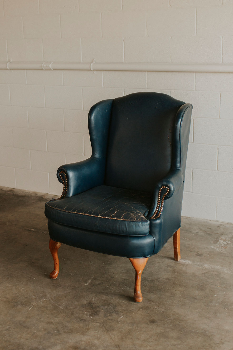 Thumbnail: Aged dark blue leather wingback armchair