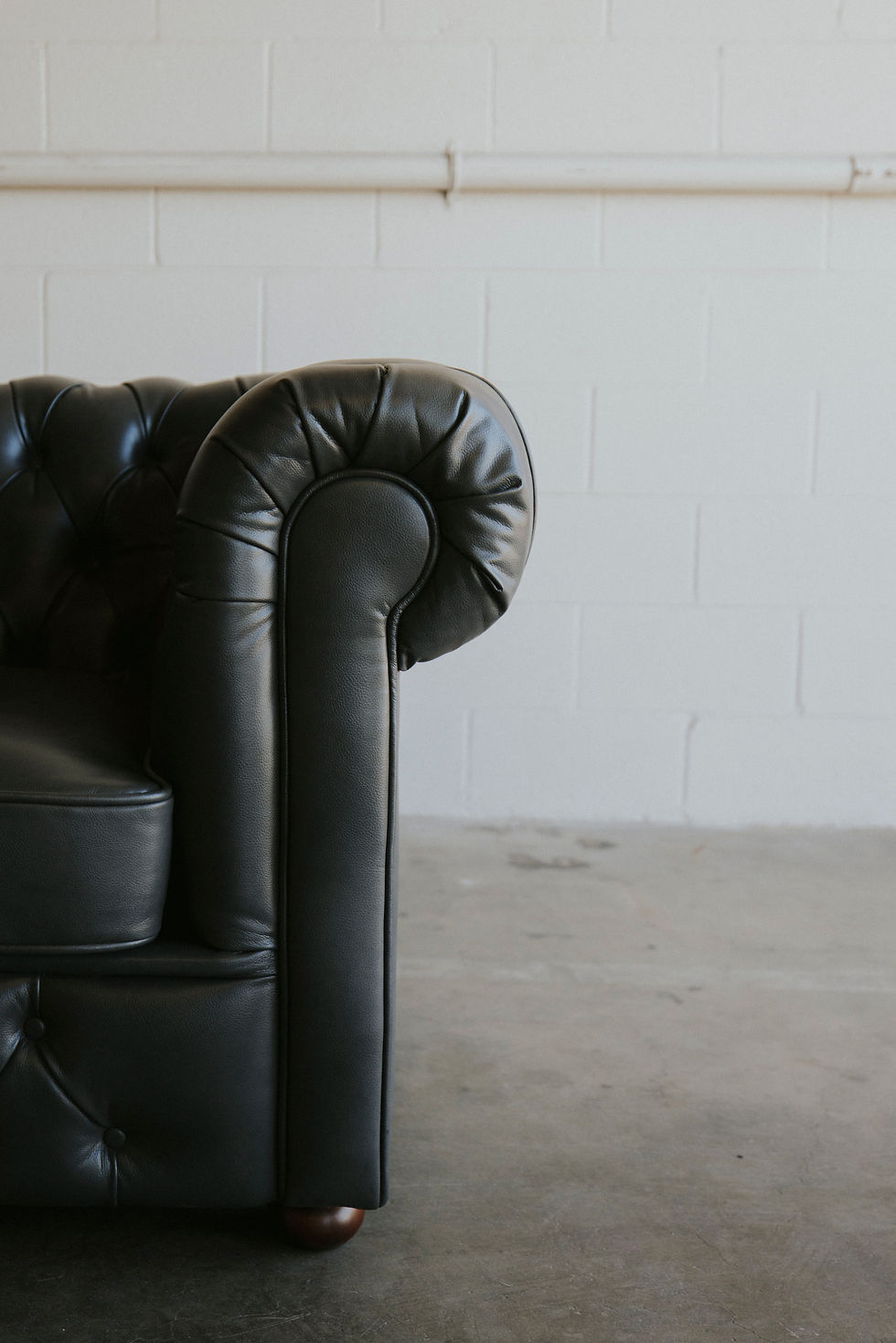 Thumbnail: Black tufted leather sofa armrest