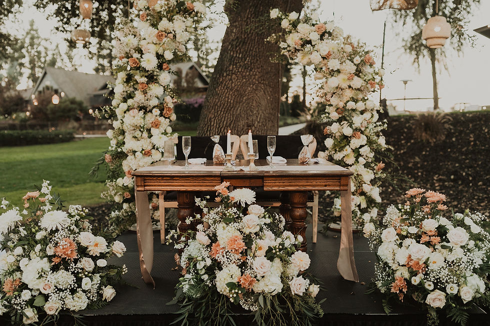 Thumbnail: Table with champagne flutes, white and peach floral arches.