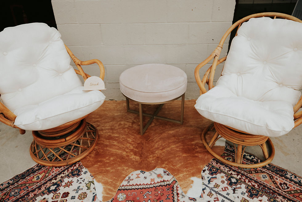 Thumbnail: Two wicker chairs with a round ottoman on a hide rug