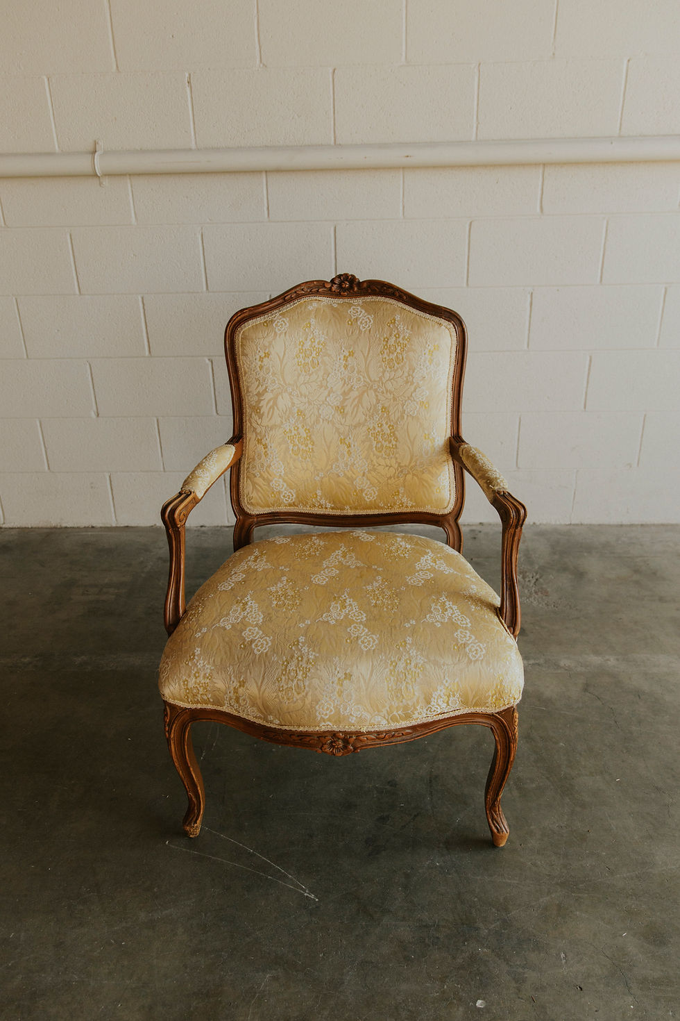 Ornate wooden armchair with cream upholstery