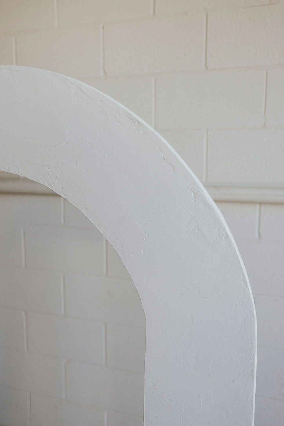 Thumbnail: White curved architectural element against brick wall.