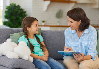 woman speaking with young female child on a sofa