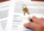 home buying contract with set of keys and a person's hand holding pen
