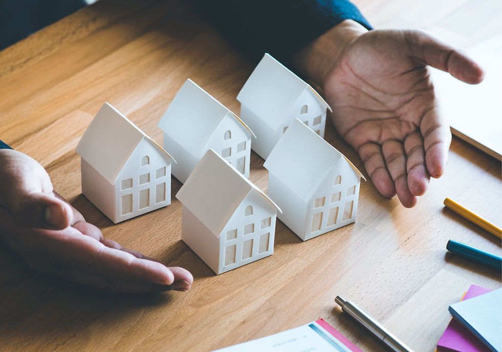 man showing 5 white miniature home models on desktop