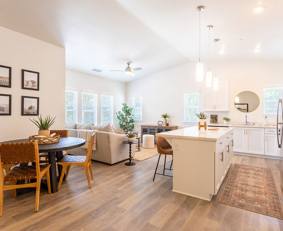 Furnished model showing kitchen and living areas with light-filled windows