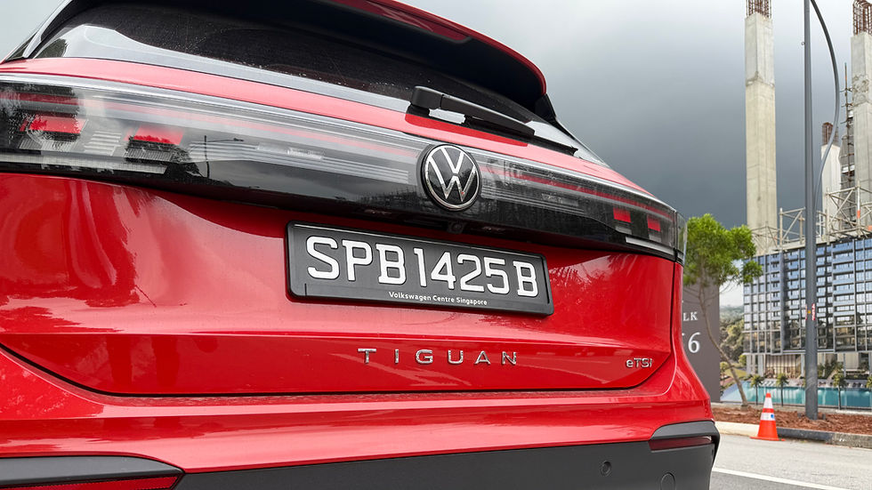 Red Volkswagen Tiguan rear with license plate SPB1425B. Construction site in the background, overcast sky.