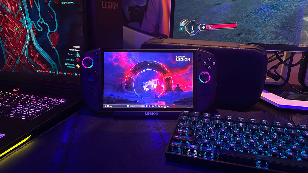 Gaming setup with Lenovo Legion handheld showing a colorful cosmic scene, flanked by a lit keyboard and laptop with a city map.