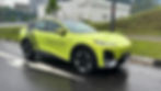 Bright green electric SUV parked on wet road near grassy area. Text on car: "Top 5 Best-Selling EV Brands in China." Building visible in background.