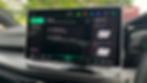 Car dashboard displaying a touchscreen with a voice assistant. Text reads "Heading home!" and "Drive safely." Bright green background.