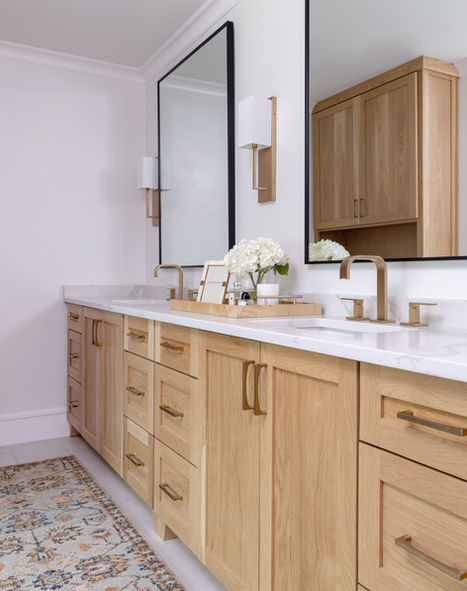 Transitional primary bathroom design with a wooden vanity, gold hardware, a runner, and a decorative tray SWI.