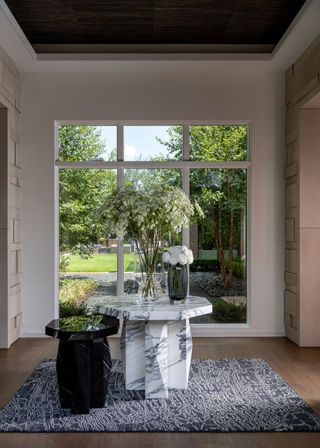 Modern entryway with windows for natural light, marble entry nesting tables, rug, and big vase with faux floral.