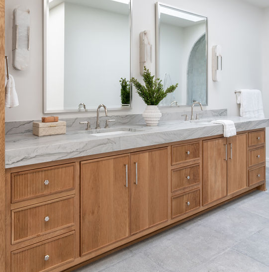 Bathroom with wooden vanity cabinet, mirrors, and marble countertop design.