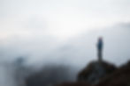 breathtaking-shot-male-standing-top-big-rock-surrounded-with-foggy-mountains