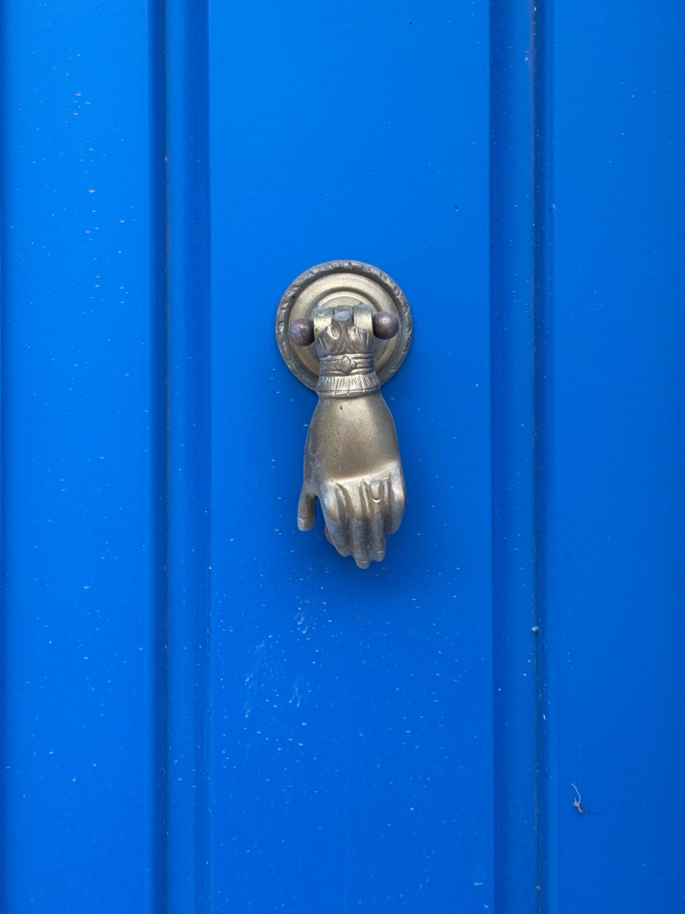 Vibrant blue door with charming hand knocker on the island of Serifos